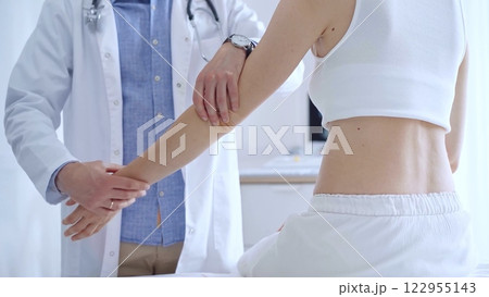 Doctor man examines a patient's elbow during a medical consultat 122955143
