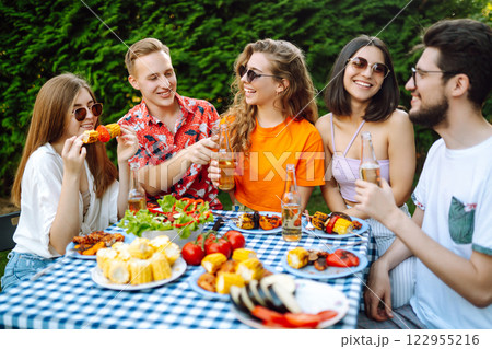 Happy friends in picnic in park. Friends grill meat, have fun, relax. ?oncept of holidays, weekends. Happy friends in picnic in park. Friends grill meat, have fun, relax. ?oncept of holidays, weekends. 122955216