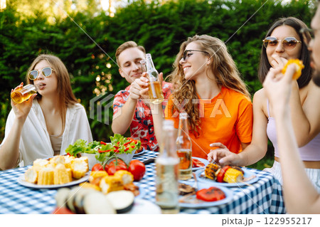 Happy friends in picnic in park. Friends grill meat, have fun, relax. ?oncept of holidays, weekends. Happy friends in picnic in park. Friends grill meat, have fun, relax. ?oncept of holidays, weekends. 122955217