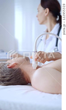 Doctor woman performing neck ultrasound exam on male patient. Medicine service concept Doctor woman performing neck ultrasound exam on male patient. Medicine service concept 122955319