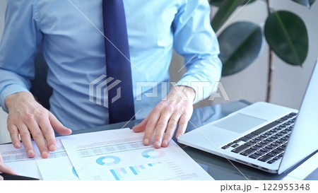 Businessman and woman analyzing data at glass desk beside a laptop in modern office, close up view. Business concept Businessman and woman analyzing data at glass desk beside a laptop in modern office, close up view. Business concept 122955348