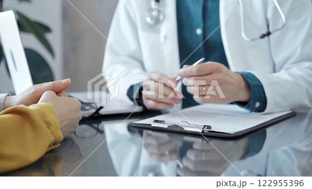 Doctor and patient consultation in clinic. Patient listens attentively as a doctor explains a diagnosis in a modern medical office. Medicine and health care Doctor and patient consultation in clinic. Patient listens attentively as a doctor explains a diagnosis in a modern medical office. Medicine and health care 122955396