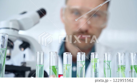 Man researcher with safety glasses is working with lab tubes using a pipette in laboratory, close-up of lab equipment. Science and medicine 122955562