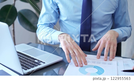 Businessman and woman analyzing data at glass desk beside a laptop in modern office, close up view. Business concept 122955563