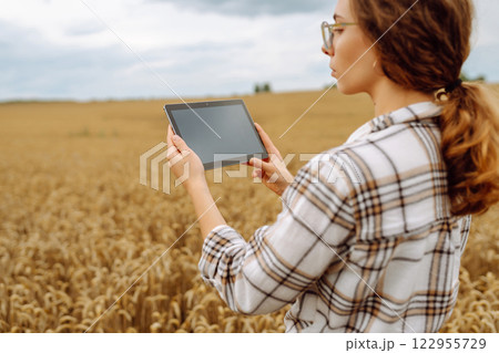 Woman farmer with digital tablet in agricultural field. Smart farm Woman farmer with digital tablet in agricultural field. Smart farm 122955729