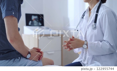 Doctor woman is taking notes on a clipboard while a male patient describes his symptoms in clinic procedure cabinet. Medicine service 122955744