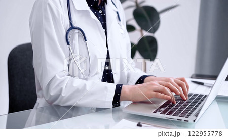 Doctor woman is using laptop computer at glass table in clinic. Medicine and pharmacy concept 122955778