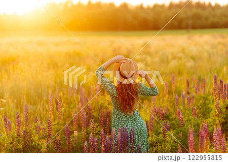 A beautiful woman with a bouquet of lupins, collects flowers, inhales fresh floral air. A beautiful woman with a bouquet of lupins, collects flowers, inhales fresh floral air. 122955815