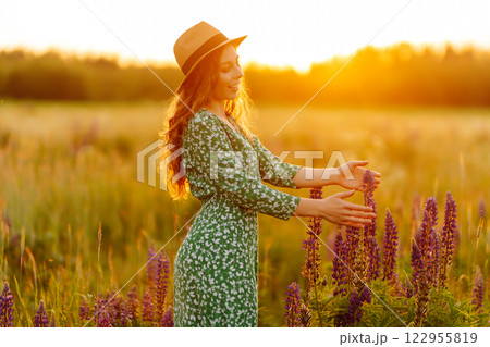 A beautiful woman with a bouquet of lupins, collects flowers, inhales fresh floral air. A beautiful woman with a bouquet of lupins, collects flowers, inhales fresh floral air. 122955819