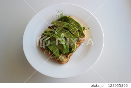 Sandwich with avocado and organic greens on gluten-free bread on a white plate flat lay stock photo 122955896