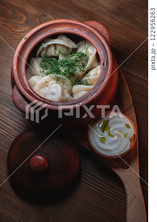 Hot, juicy dumplings snuggled in a pot. Next to it 122956263