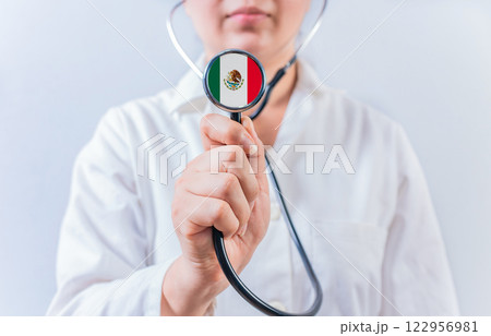 Female doctor holding stethoscope with Mexico flag. National Health System of Mexico Female doctor holding stethoscope with Mexico flag. National Health System of Mexico 122956981