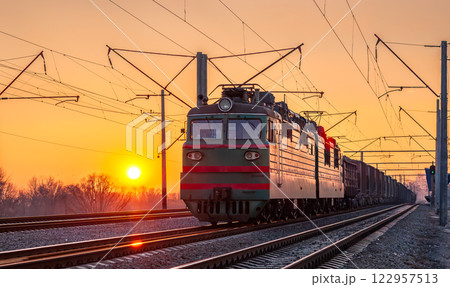 Old Soviet electric locomotive with a heavy freight train at sunset in Kyiv, the capital of Ukraine 122957513
