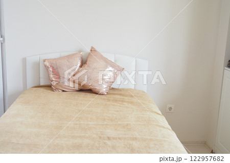 Cozy bedroom with golden accents and decorative pillows 122957682