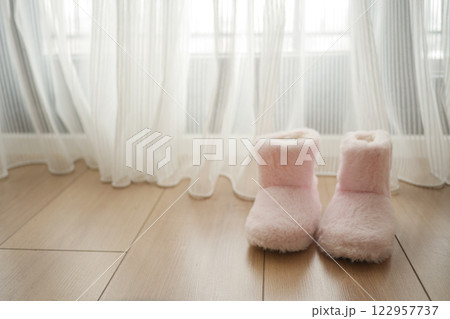 Cozy pink slippers near a window on a wooden floor Cozy pink slippers near a window on a wooden floor 122957737