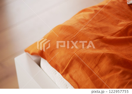 Cozy bedroom with orange linen blanket on a white bed frame Cozy bedroom with orange linen blanket on a white bed frame 122957755