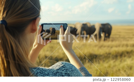 Woman Embarking On An African Wildlife Safari: Capturing A Herd Of Wild African Elephants With A Smartphone In An Open Roof Safari Vehicle With Focused Attention On Elephants. 122958060