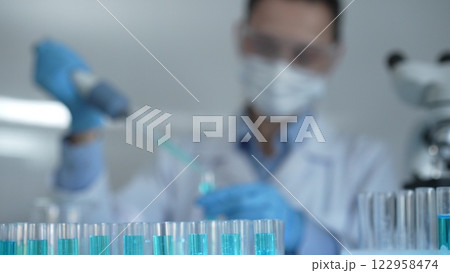 Laboratory tubes are in focus, closeup view. Female scientist researcher is using a micropipette at the background. Medicine and science concept Laboratory tubes are in focus, closeup view. Female scientist researcher is using a micropipette at the background. Medicine and science concept 122958474
