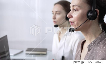 Focused female call center operator in brawn dotted blouse is assisting clients online, providing customer support and answering inquiries. Call center operators Focused female call center operator in brawn dotted blouse is assisting clients online, providing customer support and answering inquiries. Call center operators 122958675