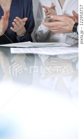 Business people or lawyers are applauding and celebrating achievements at glass table after successful meeting, vertical close up view. Concept of success Business people or lawyers are applauding and celebrating achievements at glass table after successful meeting, vertical close up view. Concept of success 122958717