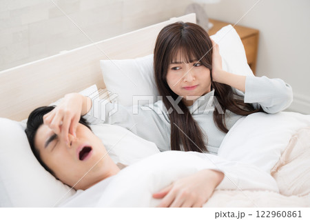 夫やパートナーのイビキがうるさくて眠れなかった女性　鼻をつまむ 122960861