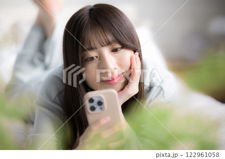 寝転んでスマホを見る若い女性のクローズアップ 122961058