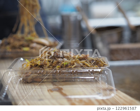 焼きそばをパックに詰める料理人の手元 122961587