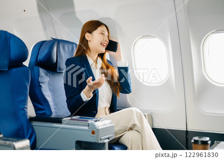 Young Asian executive excels in first class, multitasking with digital tablet, laptop and smartphone 122961830