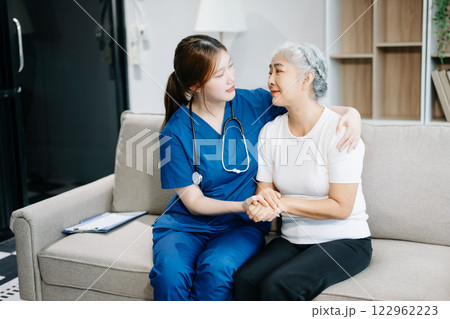 Asian caregiver doctor examine older patient use blood pressure gauge. woman therapist nurse at nursing home taking care of senior elderly 122962223