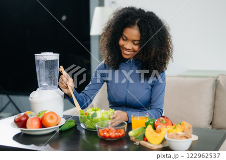 A fit woman enjoys a fresh salad with fruits and juice, embodying wellness, nutrition, and vitality 122962537