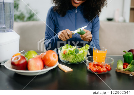 A fit woman enjoys a fresh salad with fruits and juice, embodying wellness, nutrition, and vitality 122962544