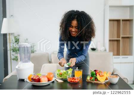 A fit woman enjoys a fresh salad with fruits and juice, embodying wellness, nutrition, and vitality A fit woman enjoys a fresh salad with fruits and juice, embodying wellness, nutrition, and vitality 122962555