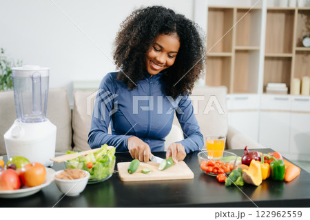 A fit woman enjoys a fresh salad with fruits and juice, embodying wellness, nutrition, and vitality 122962559