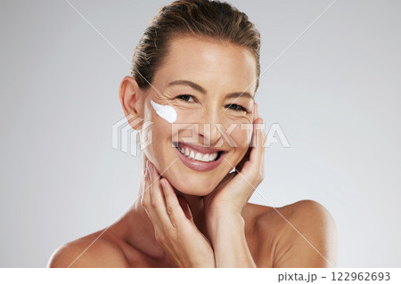 Cream, face wellness and mature woman with skincare product for health against a grey mockup studio background. Portrait of model with smile and happy about dermatology sunscreen with mock up space 122962693