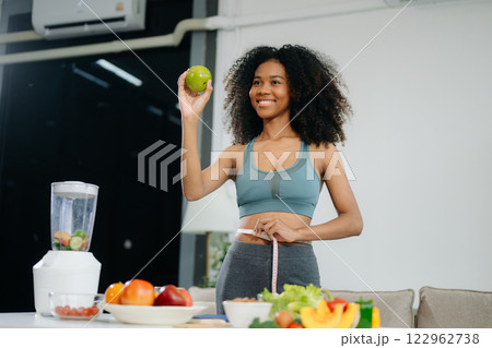 Smiling woman measuring waist, holding green apple with fruits, veggies, Smiling woman measuring waist, holding green apple with fruits, veggies, 122962738