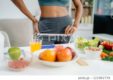 Smiling woman measuring waist, holding green apple with fruits, veggies, Smiling woman measuring waist, holding green apple with fruits, veggies, 122962739