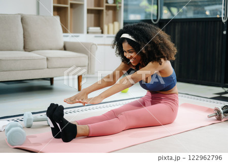 Woman Doing Yoga and Watching Online Tutorials on Laptop, Training in Living Room at home 122962796