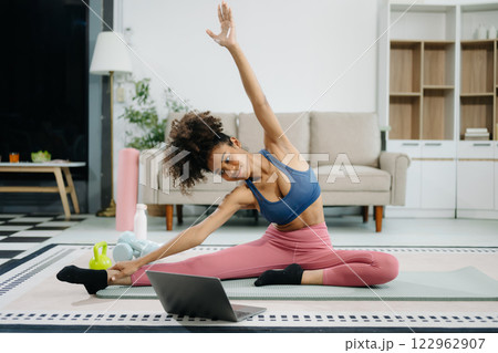 A young woman practices yoga and stretching with a mat and gym props, showcasing wellness, motivation, 122962907