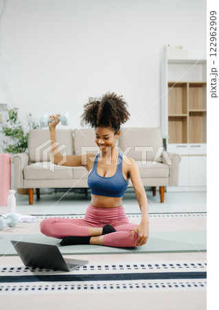 Woman Doing Yoga and Watching Online Tutorials on Laptop, Training in Living Room at home 122962909