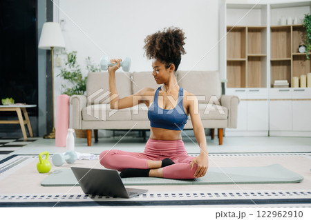 Woman Doing Yoga and Watching Online Tutorials on Laptop, Training in Living Room at home 122962910