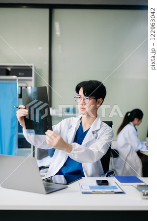 Doctor analyzing patient data on tablet in clinical lab. Medical professional in hospital with laptop, blood samples 122963042