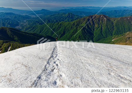 谷川岳山頂直下の雪渓を行く登山者とみなかみ町方面の眺め 122963135