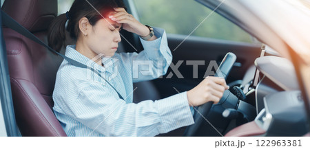 woman feeling stress and angry during drive car long time. Asian girl tired and fatigue having headache after driving car in traffic jam. Sleepy, stretching and drunk concept 122963381