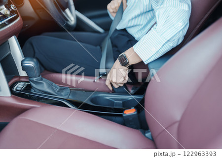 Business woman driver hand fastening seat belt during sitting inside a car and driving in the road. safety, trip, journey and transport concept 122963393