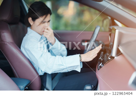 Asian woman hold nose because bad smell after turn on air conditioning in car. Woman driving car with broken air conditioning in hot summer weather. Businesswoman driver is tired, overheat and stress Asian woman hold nose because bad smell after turn on air conditioning in car. Woman driving car with broken air conditioning in hot summer weather. Businesswoman driver is tired, overheat and stress 122963404
