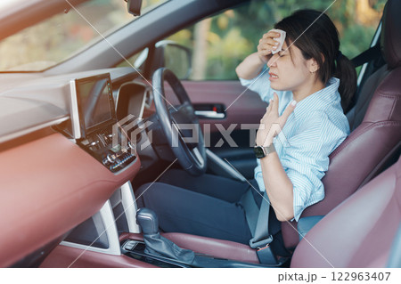 woman driving car with broken air conditioner in hot summer weather, uses tissue paper napkin to wipe the sweat off her forehead. Businesswoman driver is tired, Exhausted overheated and stressed woman driving car with broken air conditioner in hot summer weather, uses tissue paper napkin to wipe the sweat off her forehead. Businesswoman driver is tired, Exhausted overheated and stressed 122963407