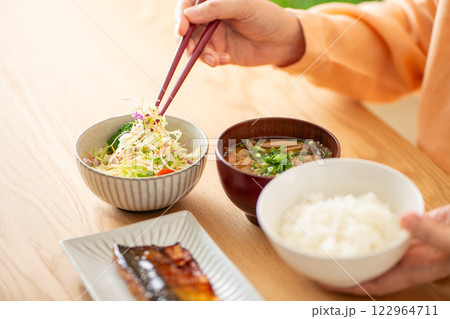 和食の朝食でサラダを食べるミドル女性 122964711