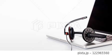 A sleek headset resting on a laptop, set against a bright white background 122965560
