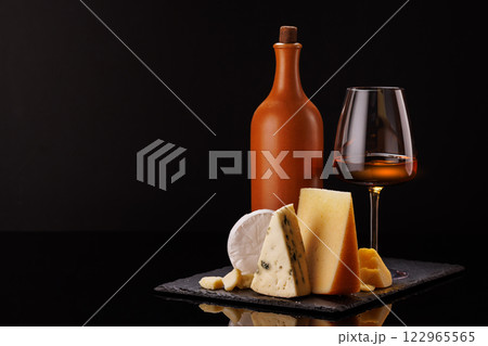 A refined selection of aged cheeses presented on a board, accompanied by a glass of wine A refined selection of aged cheeses presented on a board, accompanied by a glass of wine 122965565