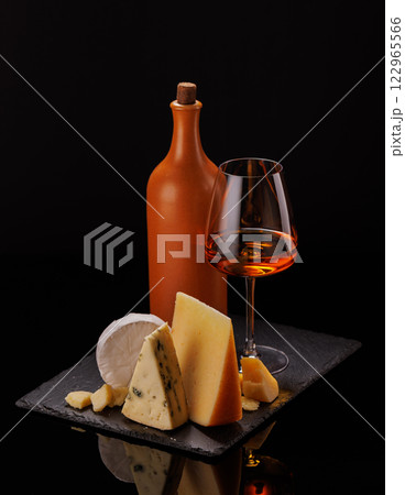A refined selection of aged cheeses presented on a board, accompanied by a glasses of wine 122965566
